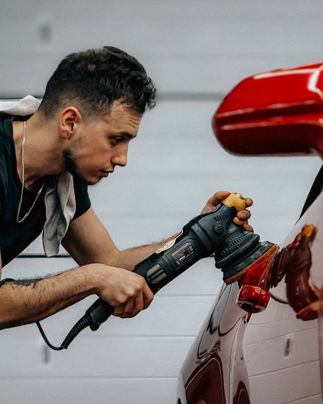 A car detailer polishing a car